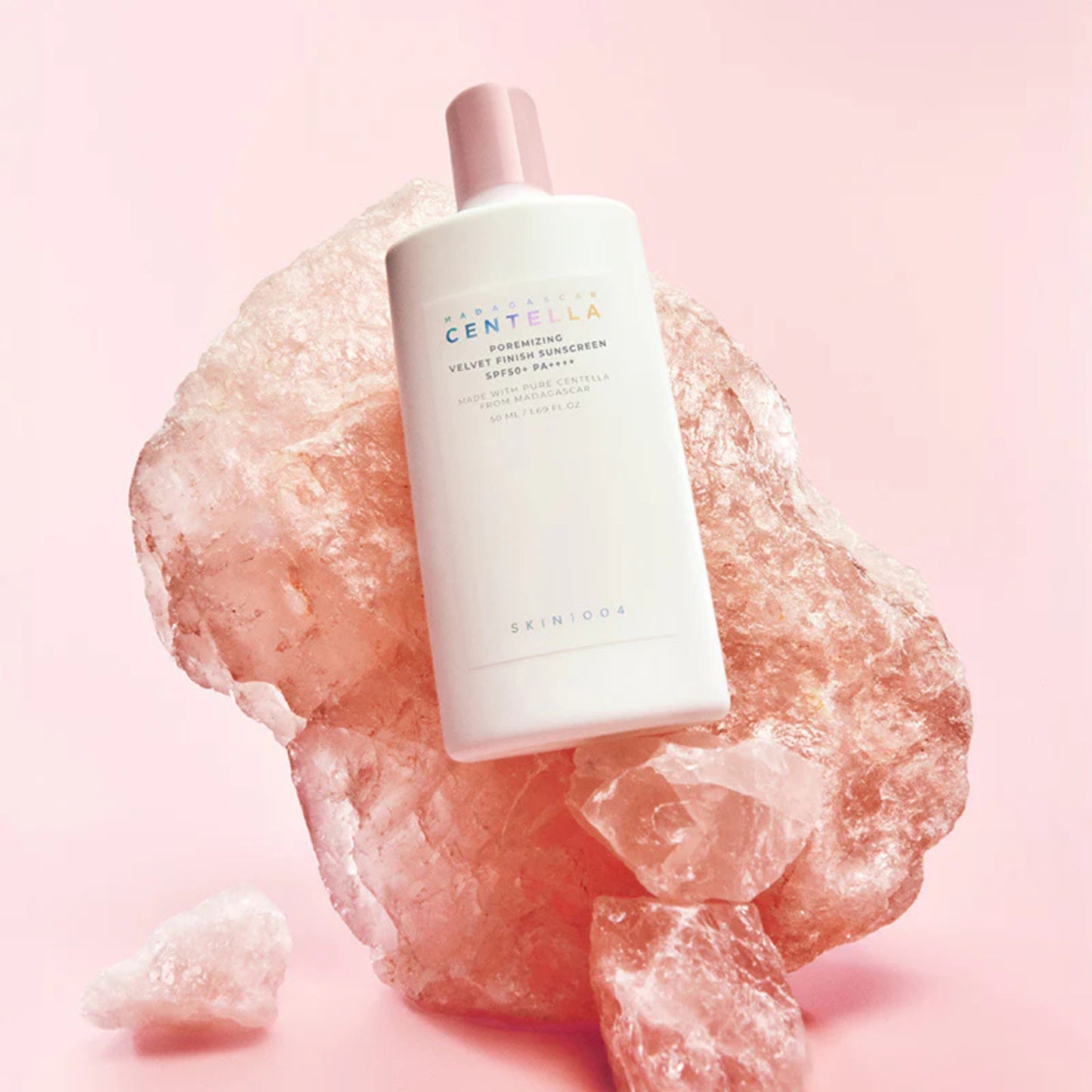 Skincare bottle on a pink rock with a soft pink background